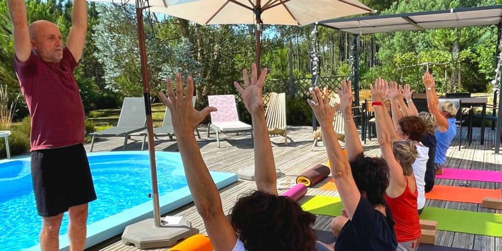 Photo de Mehdi animant le cours de yoga sur la terrasse face à la piscine.