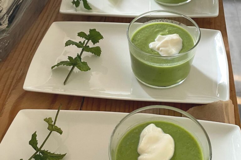 Photo d'assiettes servies avec des petites verrines vertes et leur branche de menthe.