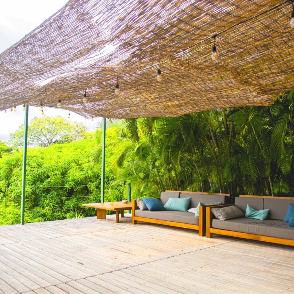 Terrasse en bois et végétation verdoyante recouverte d'une paillotte.