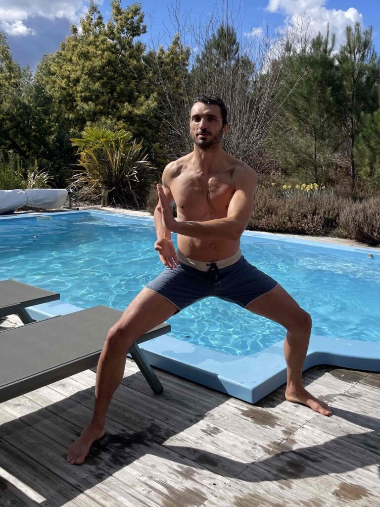 Photo d'un homme torse nu en exercice de respiration devant une piscine.