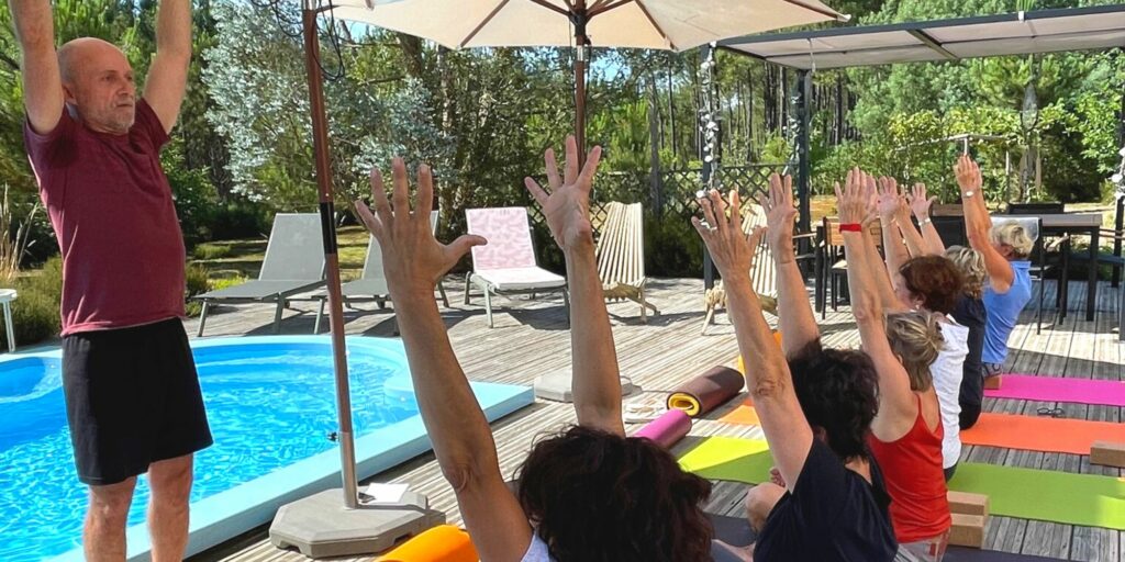 Photo d'un group de personnes au bord de la piscine en train de pratiquer un cours de yoga.