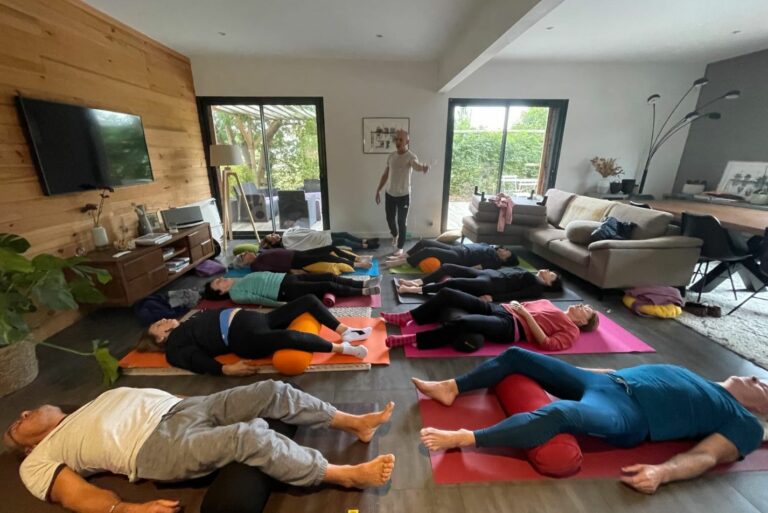 Photo d'un groupe de yoga avec postures au sol.