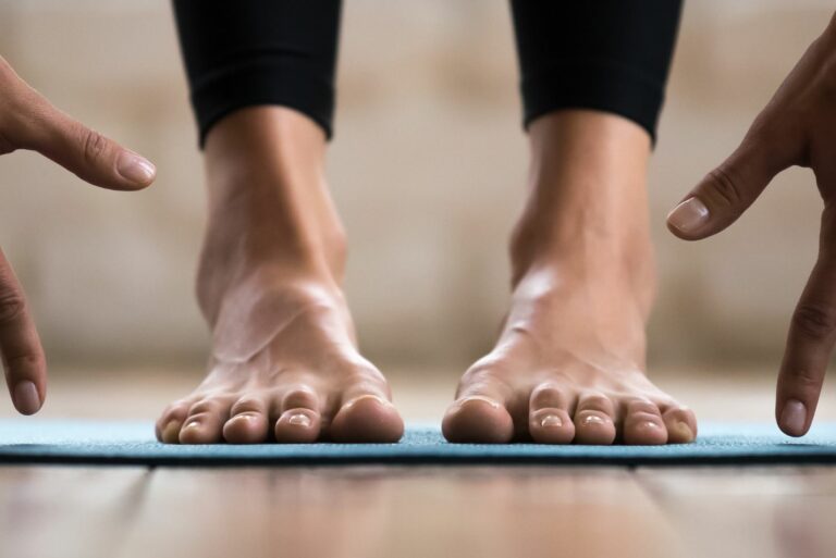 Photo de pieds et mains d'une personne en train de faire du yoga sur un tapis.
