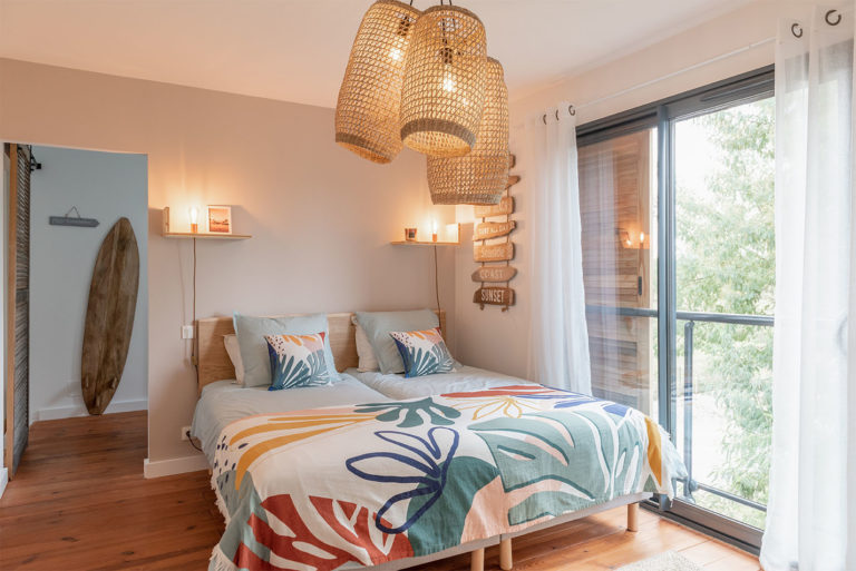 Photo de la chambre Mimizan avec son inspiration colorée et surf et baie vitrée.