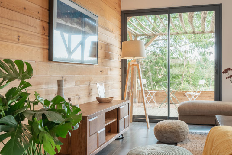 Photo d'un salon avec mur en bois et baie vitrée donnant sur une pergola.