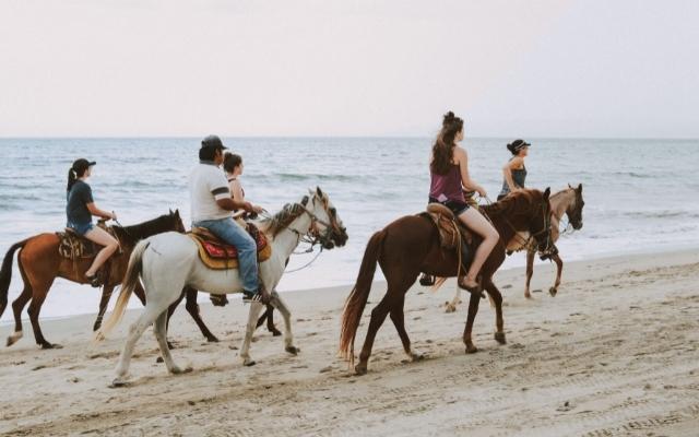 Photo de 5 personnes à cheval sur la plage au Costa Rica.