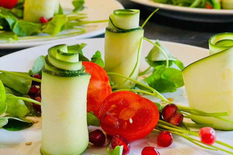 Photo d'une jolie présentation de légumes roulés de courgette avec tomate cerise et grenade.