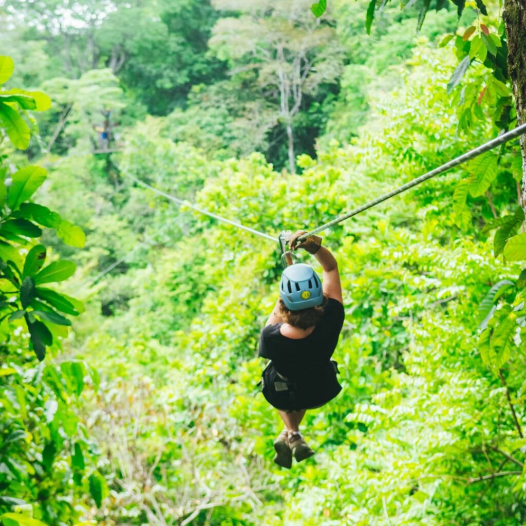 Photo d'une personne en tyrolienne survolant la jungle.
