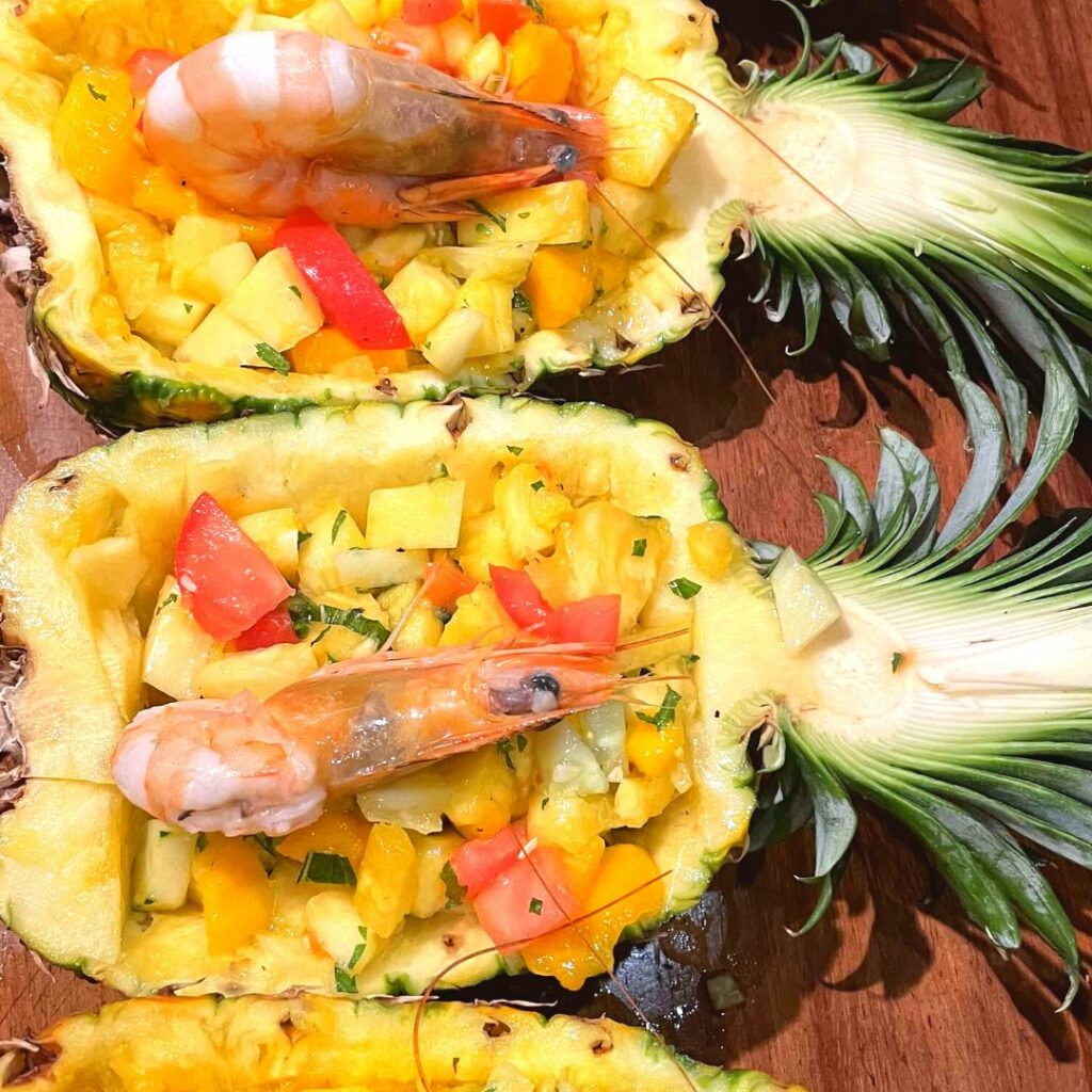 Photo de demis ananas servis avec un mix de légumes et une crevette.