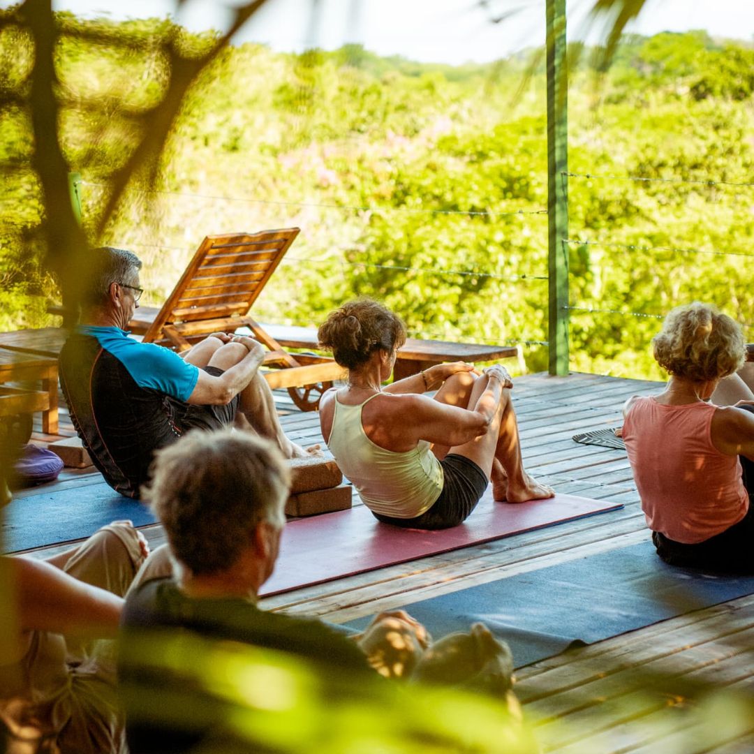 Photo d'un groupe de yoga en posture assise au sol avec fond de verdure au Costa Rica.