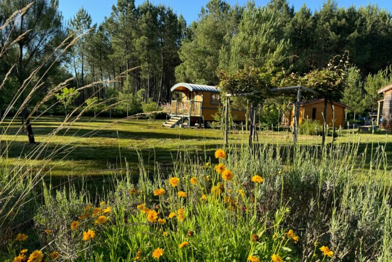 Photo d'une roulotte au fond d'un jardin fleuri et bien vert dans les Landes.